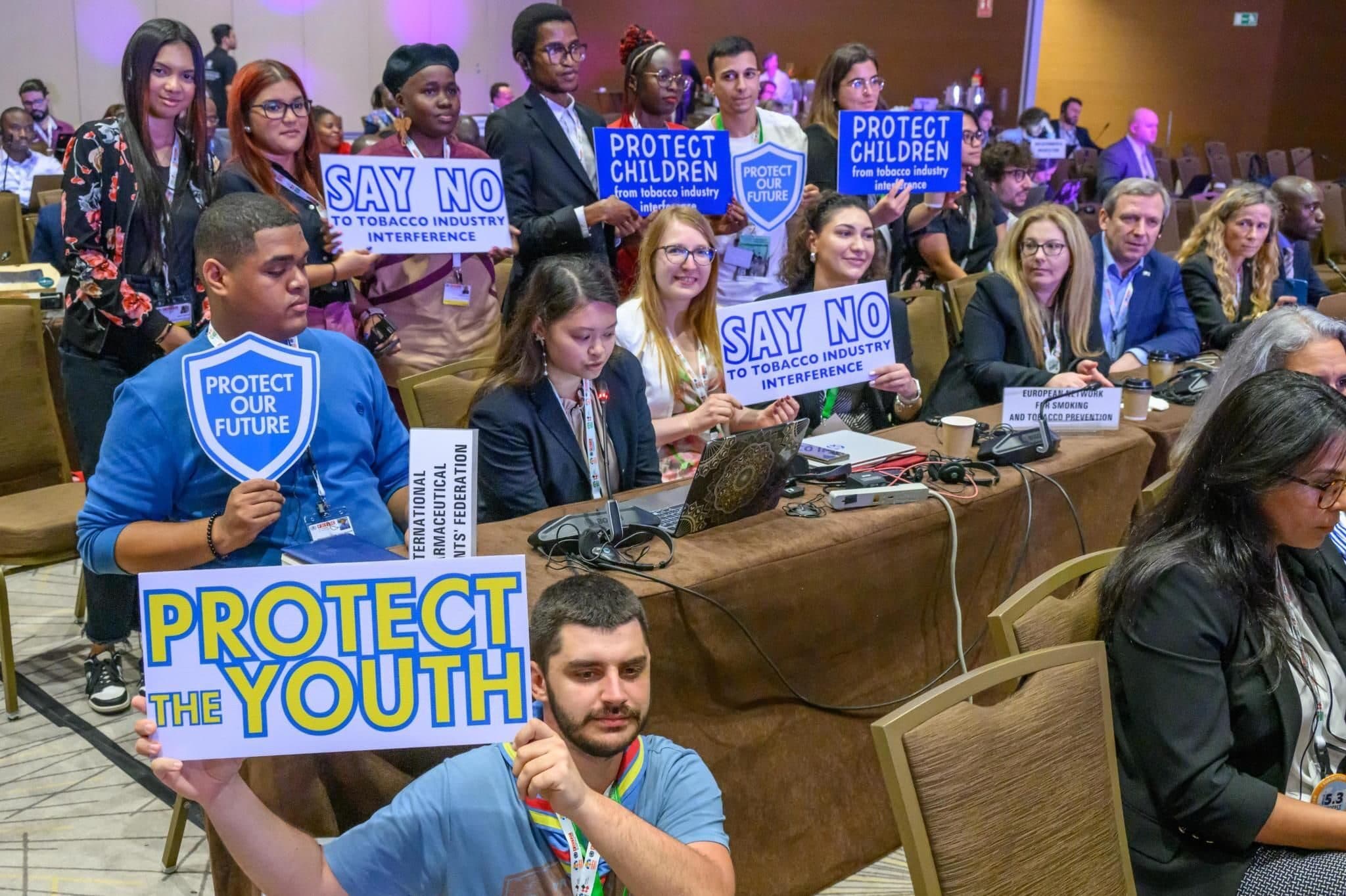 Youth delegates at WHO FCTC COP10 holding placards that read “Protect the youth”, “Say no to tobacco industry interference” and “Protect children from tobacco industry interference”
