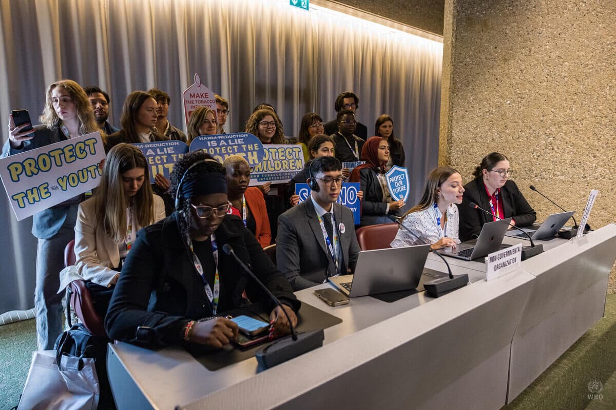 Youth advocates behind the non-governmental organization desk at WHO FCTC COP11 holding placards that read “Protect the youth”, “Harm reduction is a lie” and “Protect children”